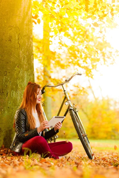 Mujer en el parque de otoño usando tableta de lectura —  Fotos de Stock