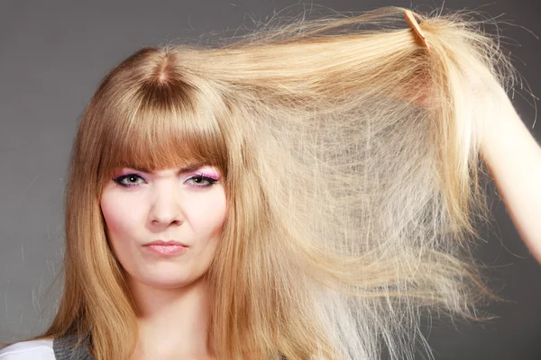 Blondýnka česání suché vlasy. — Stock fotografie
