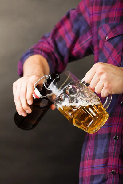 Jonge man gieten bier uit fles in mok — Stockfoto