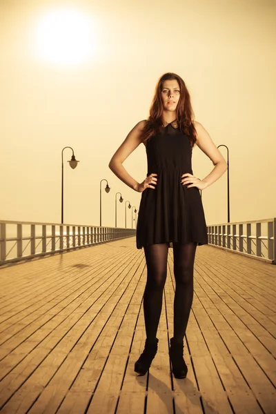 Woman posing on pier at sunrise — Stock Photo, Image