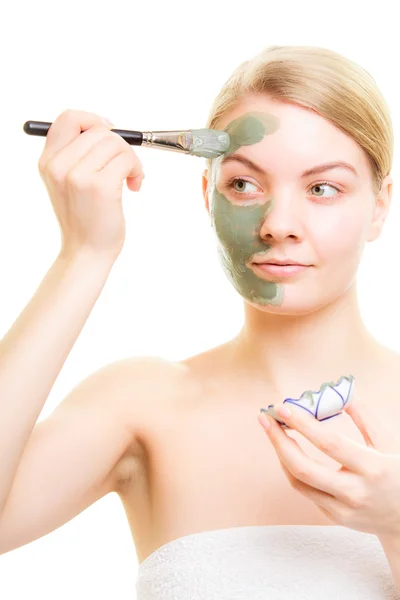 Woman applying clay mask