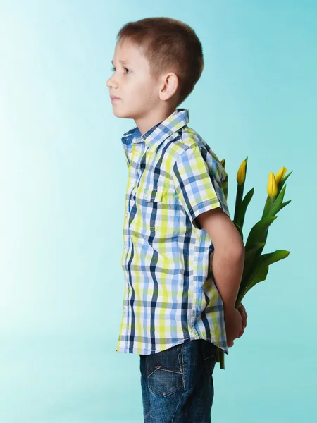 Menino escondendo buquê de flores atrás de si — Fotografia de Stock