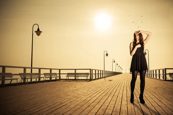 Frau posiert bei Sonnenaufgang auf Pier — Stockfoto