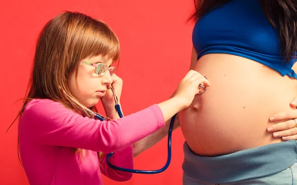 Petite fille écoutant le ventre de la mère — Photo