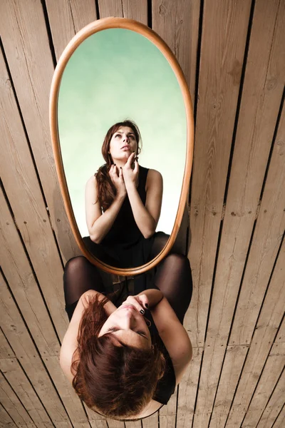 Thoughtful woman looks at reflection in mirror — Stock Photo, Image