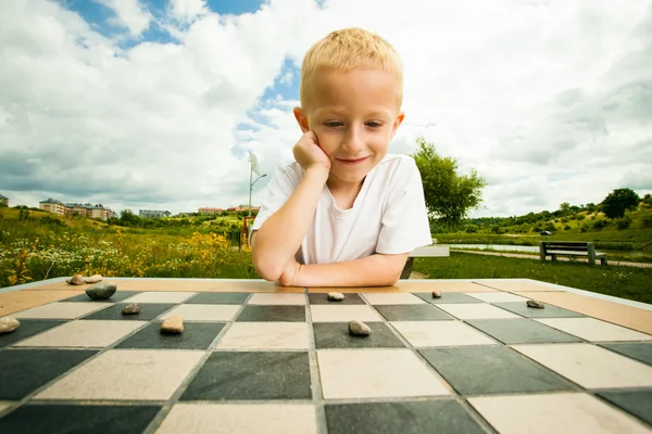 Child playing draughts or checkers board game outdoor — Stock Photo, Image