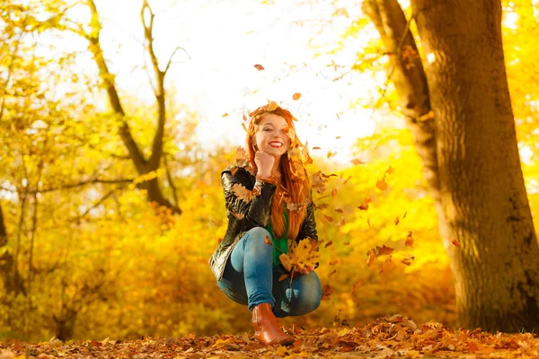 Κορίτσι χαλαρωτικό στο πάρκο φθινόπωρο ρίχνουν φύλλα στον αέρα. — Φωτογραφία Αρχείου