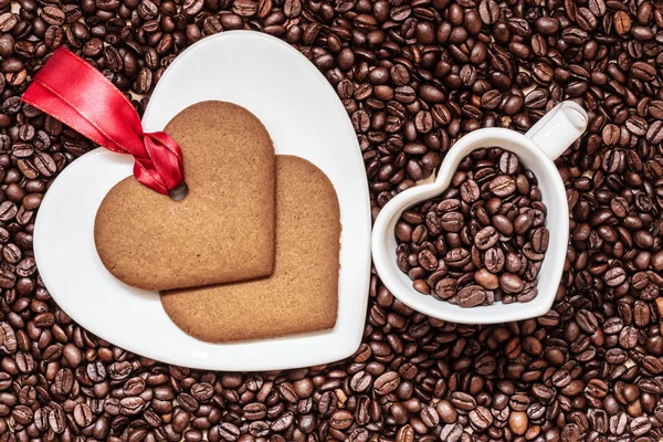 Coração em forma de copo e biscoito no fundo grãos de café — Fotografia de Stock