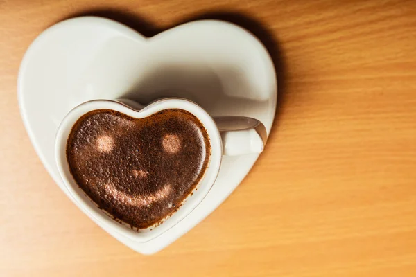 Coffee in heart shaped cup with smile face sign — Stock Photo, Image