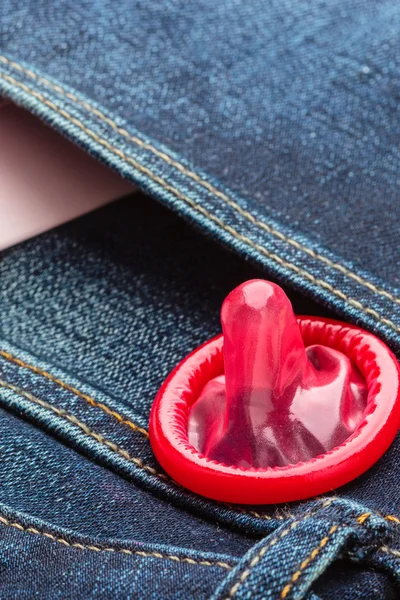 Rood condoom op jeans zak. — Stockfoto