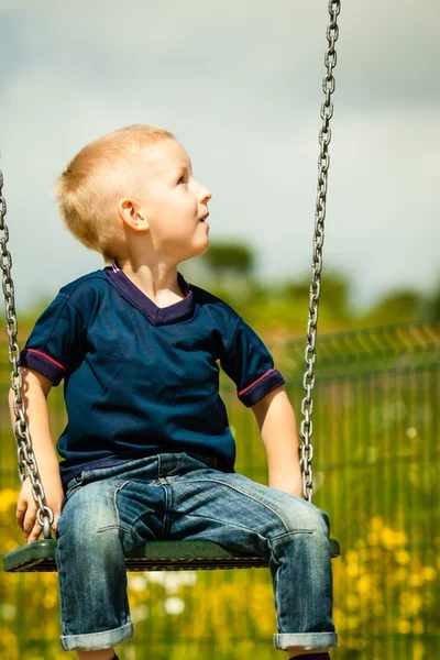 Little blonde boy child having fun on a swing outdoor — Stock Photo, Image