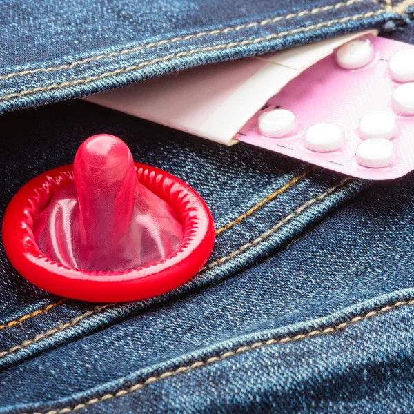 Pills and condom in denim pocket. — Stock Photo, Image