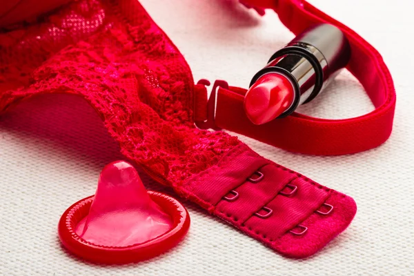 Lipstick and condom with lace lingerie. — Stock Photo, Image
