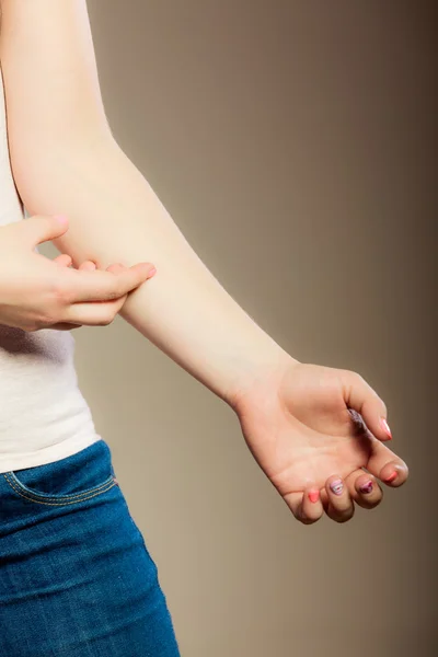 Vrouw die aan haar arm krabt — Stockfoto