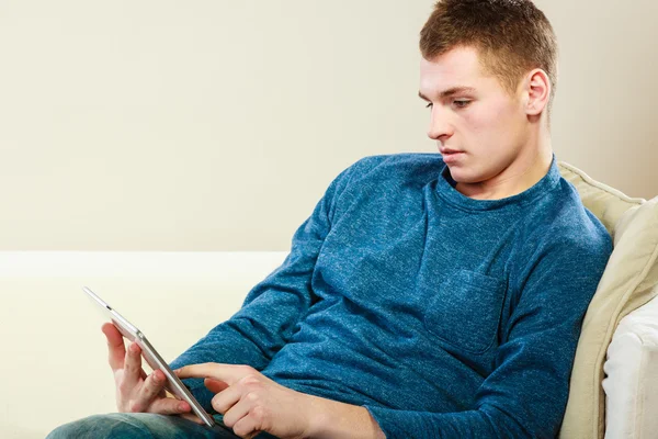 Joven con la tableta sentado en el sofá en casa —  Fotos de Stock