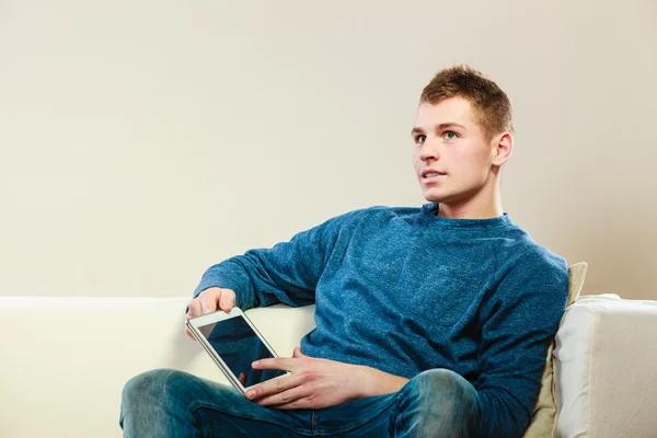 Молодий чоловік з цифровим планшетом сидить на дивані — стокове фото