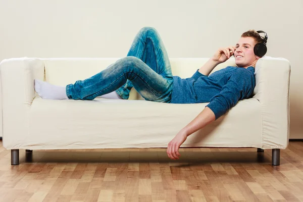 Junger Mann mit Kopfhörern auf Couch liegend — Stockfoto