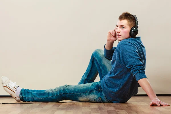 Ung man med hörlurar sittande på golvet — Stockfoto