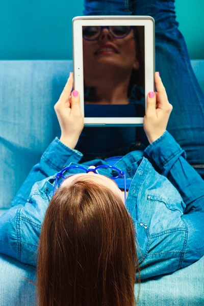 Žena s tabletem relaxační na gauč modré barvy — Stock fotografie