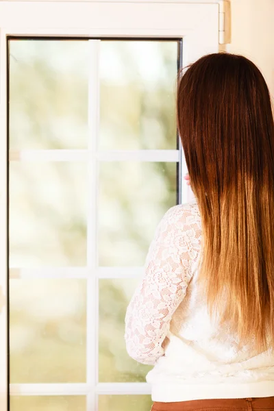 Schöne Frau schaut durch Fenster. — Stockfoto