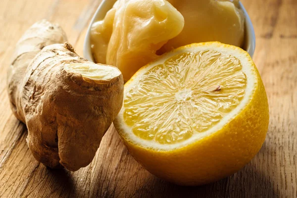 Корень имбиря, мед и лимон на деревянном деревенском столе. — стоковое фото