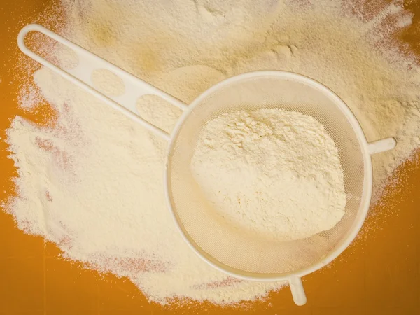 Sifting wheat flour on orange mat — Stock Photo, Image