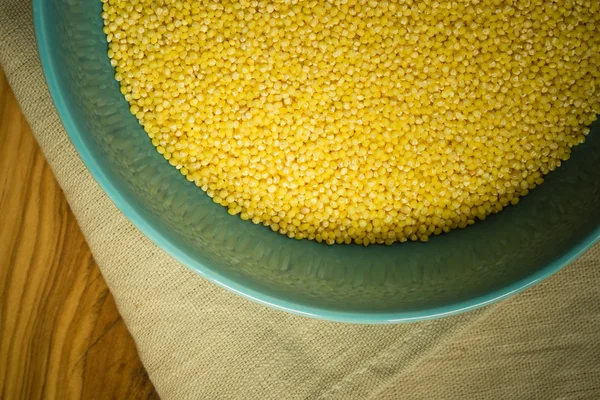 Millet groats in blue bowl on wooden table — Stock Photo, Image