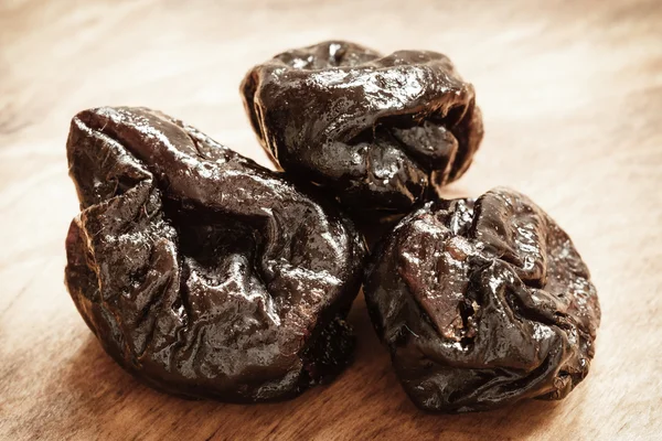 Dried plums prunes on wooden table — Stock Photo, Image