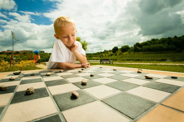 Bambino che gioca a dama o dama gioco da tavolo all'aperto — Foto Stock