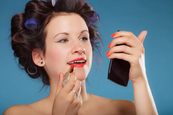 Chica en rulos de pelo aplicando lápiz labial rojo — Foto de Stock