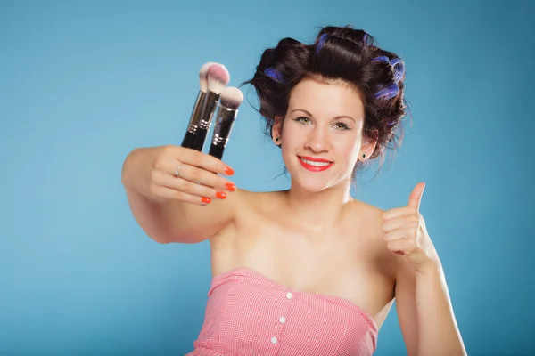Woman in hair rollers holds makeup brushes — Stock Photo, Image