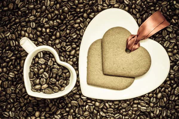Srdce ve tvaru pohár a sušenky na kávových zrn pozadí — Stock fotografie