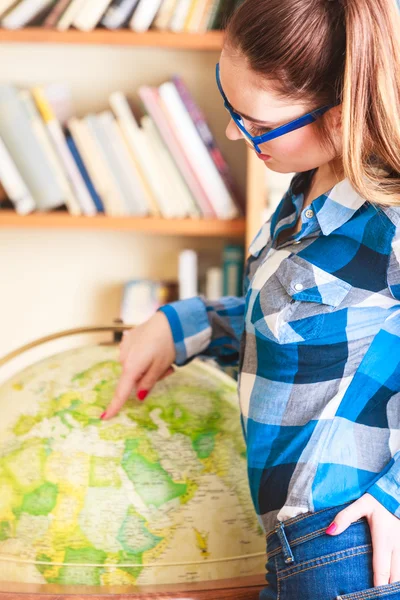 Mädchen in Bibliothek zeigt auf Globus — Stockfoto