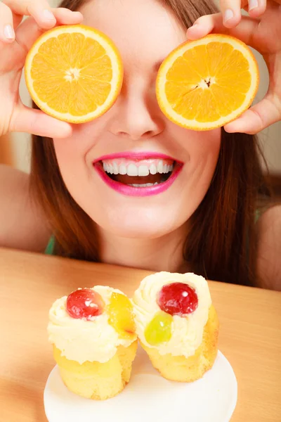 Woman with sweet cakes and orange covering eyes. — Stock Photo, Image