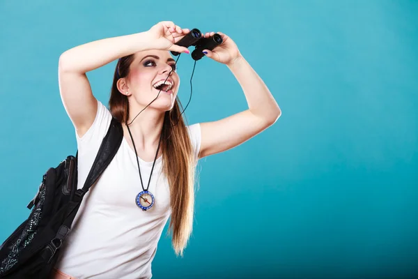 Toeristische vrouw kijkt door een verrekijker op blauw — Stockfoto