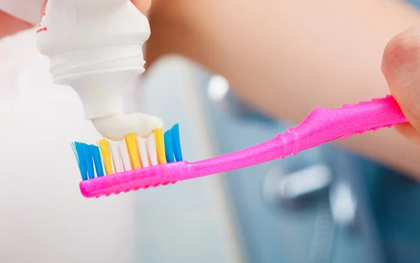 Mãos de mulher colocando pasta de dentes na escova de dentes — Fotografia de Stock