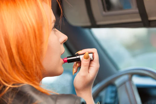 Kız araba kullanırken dudaklarını boyuyor makyaj yapıyor.. — Stok fotoğraf