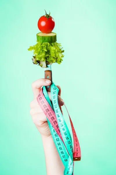 Woman hand with vegetarian food and measuring tapes. — Stock Photo, Image