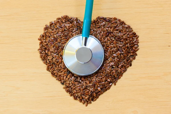 Raw flax seeds heart shaped and stethoscope — Stock Photo, Image