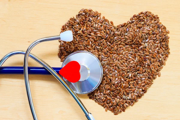Surowe nasiona lnu w kształcie serca i stetoskop — Zdjęcie stockowe
