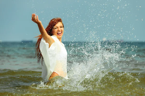 Flicka stänkande vatten att ha kul på havet. — Stockfoto