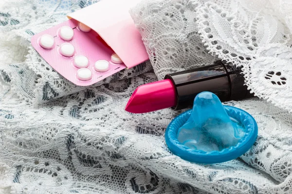 Pillen Kondom und Lippenstift auf Spitzenunterwäsche — Stockfoto