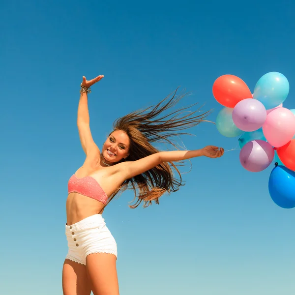 Mädchen springt mit bunten Luftballons — Stockfoto