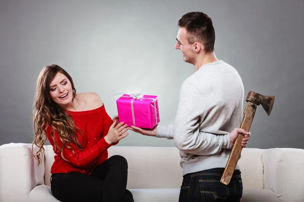 Homem insinciro segurando machado dando caixa de presente para a mulher — Fotografia de Stock