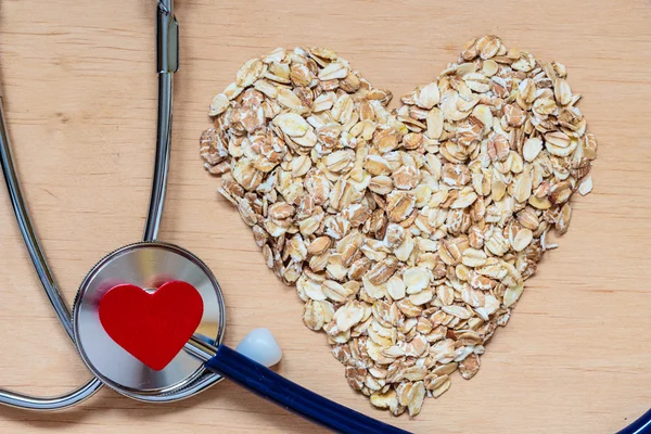 Oat flakes heart shaped and stethoscope. — Stock Photo, Image