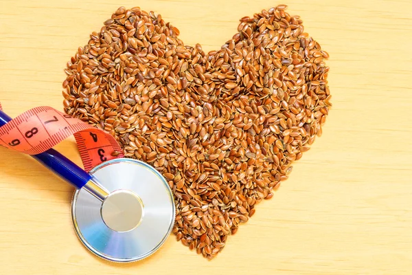 Raw flax seeds heart shaped and stethoscope — Stock Photo, Image