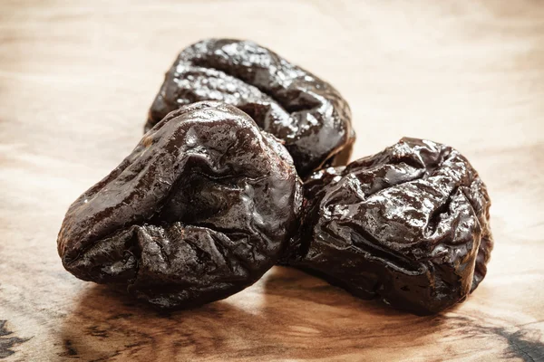 Dried plums prunes on wooden table — Stock Photo, Image