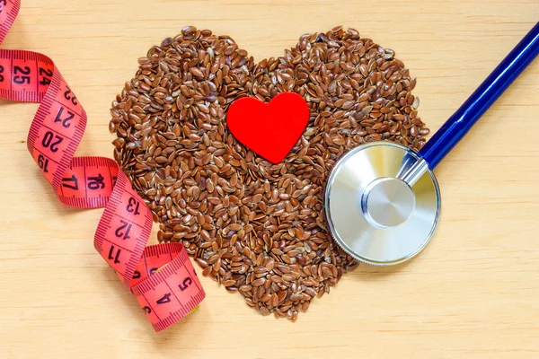 Raw flax seeds heart shaped and stethoscope — Stock Photo, Image