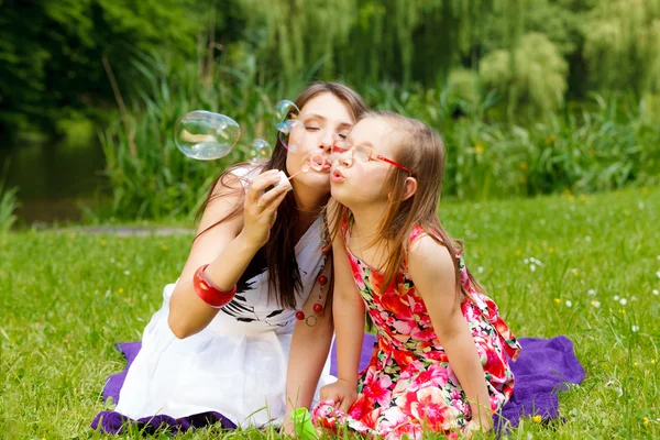 Mother and  girl blowing bubbles — Zdjęcie stockowe