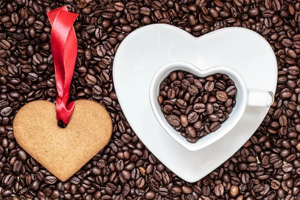 Tazza a forma di cuore e biscotti su sfondo chicchi di caffè — Foto Stock